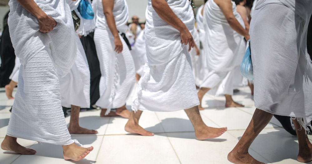 Pilgrims wearing white Ihram clothing at Miqat preparing for Umrah or Hajj, symbolizing entry into the sacred state of Ihram before pilgrimage