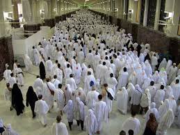 Pilgrims walking between Safa and Marwah during Sa’i in Masjid al-Haram, with one pilgrim resting due to fatigue or illness